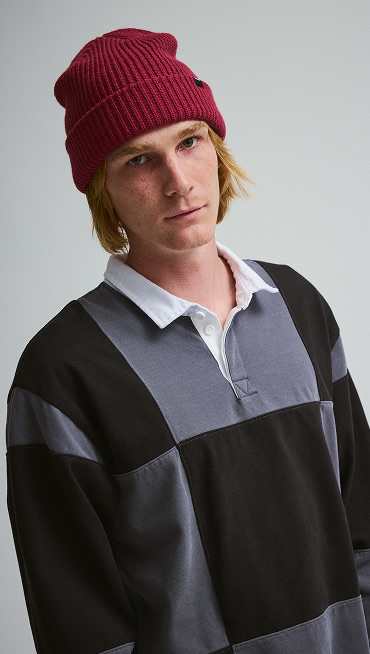Man wearing Grant Checkerboard Rugby shirt with a red beanie on a grey photography studio background.