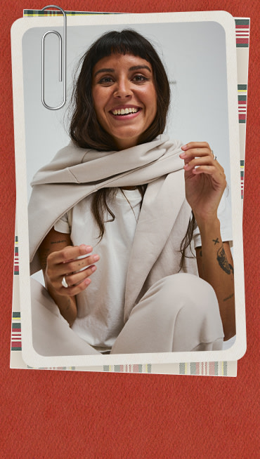 A red holiday border around an image of a woman looking into the camera in taupe mist gray Script Logo Mock Neck Sweatshirt and Drop V Sweatpants.