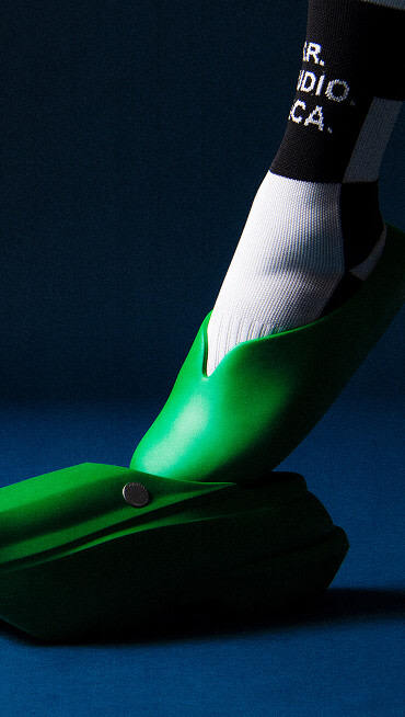 A foot sliding into the OTW by Vans x S.R. Studio LA. CA. Clog in Tamborine Green in a studio shot with blue background.