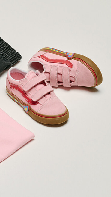 Medium shot of a pair of Toddler Old Skool V Shoe in Gum Pink laying on the floor of a grey photography studio.