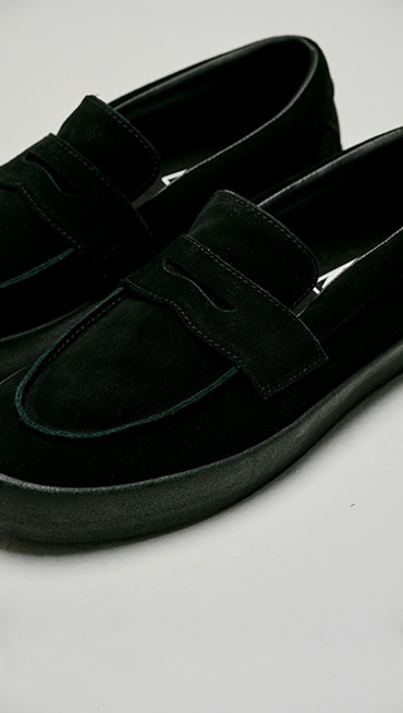 Close up of a pair of black suede Skate Loafers in a grey photography studio.
