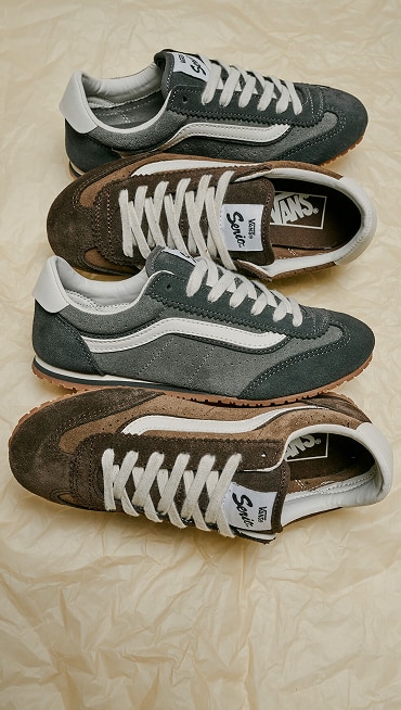 Alternating pairs Super Lowpro shoes in Demitasse Brown and Pewter Grey on the ground with a crumple paper background.