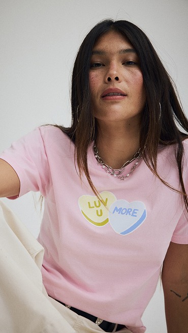 Close-up on a young woman wearing a pink Luv You More t-shirt from the Vans Valentine’s Day Collection.