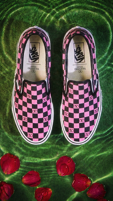 Close up overhead shot of a pair of the Classic Slip-On Valentino Shoe on green water with rose petals floating nearby.