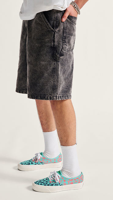 A waist-down shot of a man in black denim shorts, white crew socks, and Cheetah Pool Blue Premium Authentic.