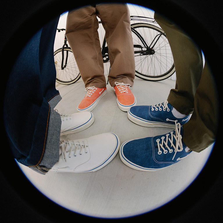 A fisheye shot of three men on a sidewalk in the navy colorway, the cayenne red colorway, and marshmallow white colorway of the Authentic Boat Shoe.