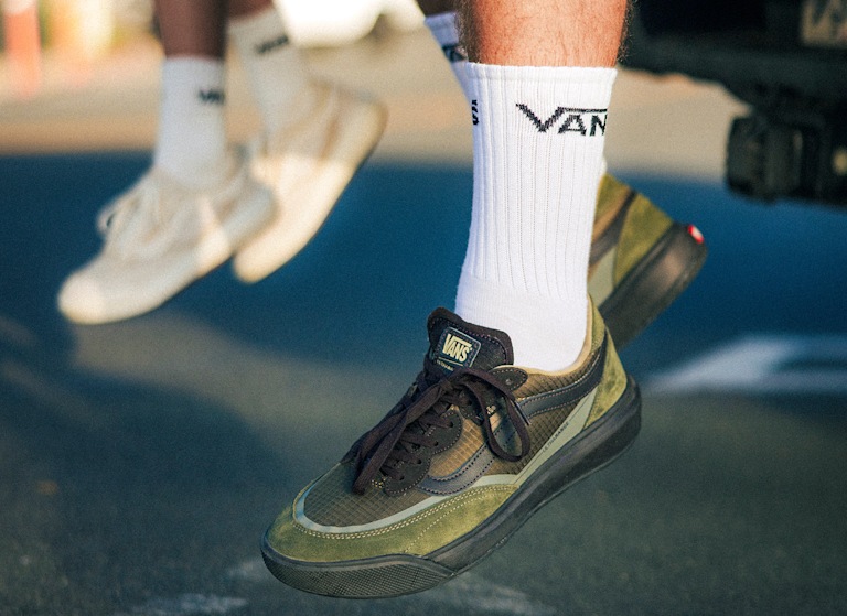 A man and woman sit on the bed of a truck, their feet dangling and wearing UltraRange 2.0.
