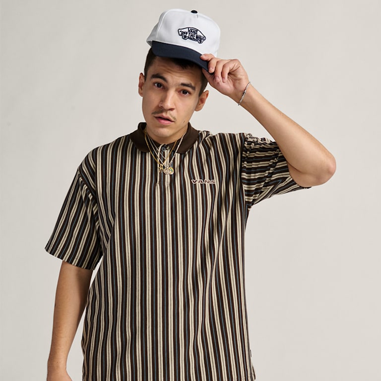 A man poses in a photography studio wearing a black and white striped shirt.