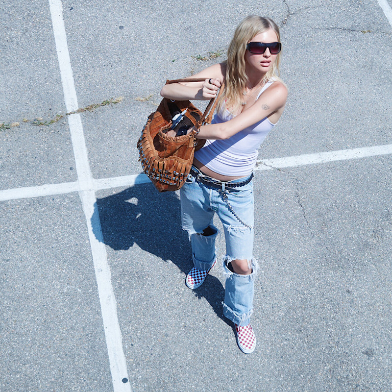 An overhead shot of model Beanie in a parking lot wearing ripped jeans and red Checkerboard Classic Slip-On on the set of Open Set Los Angeles.