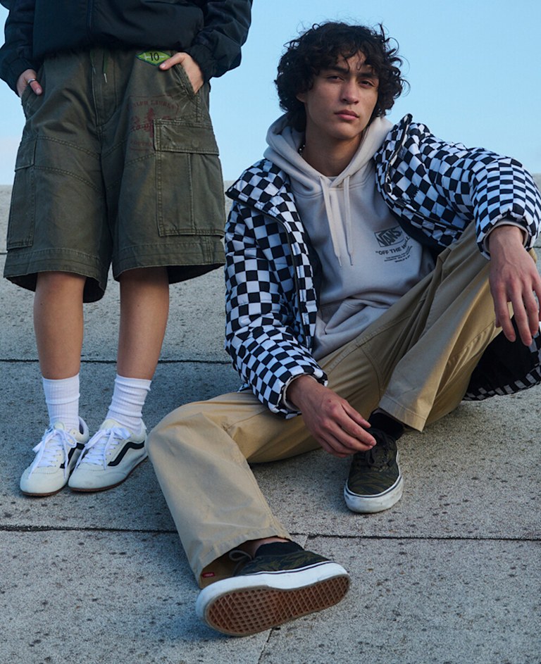 A young woman poses on a roof wearing a black hoodie, green cargo shorts, and marshmallow white Super Lowpro.