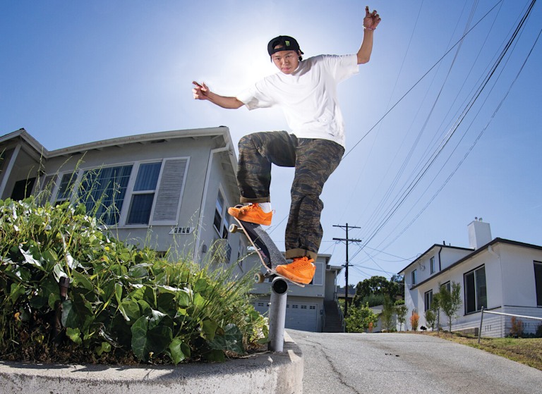 Vans Skate Team Rider Toa Sasaki grinding a rail wearing orange Skate Old Skool 36+ and camo pants from the United Through Skateboarding collection.