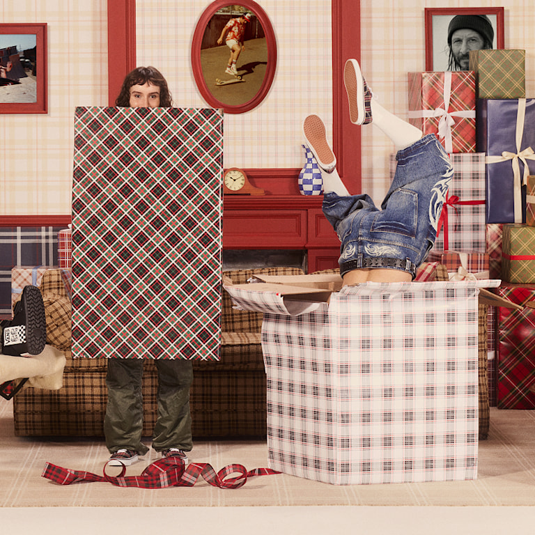 An eclectic cast of skaters, influencers, musicians and artists pose for a photo on the set of a sitcom surrounded by gifts.
