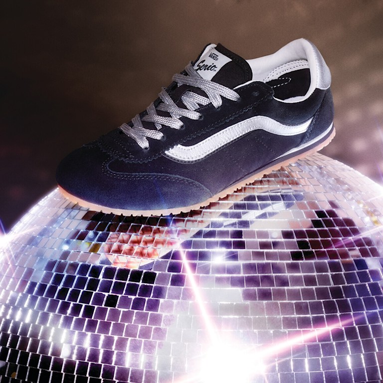 A black and silver Super Lowpro shoe rests on top of a twinkling disco ball.