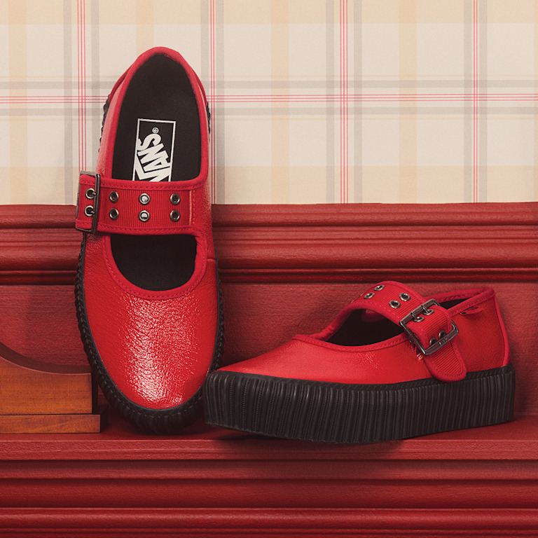 A pair of racing red Mary Jane Creeper rest on the mantle on a TV sitcom set.