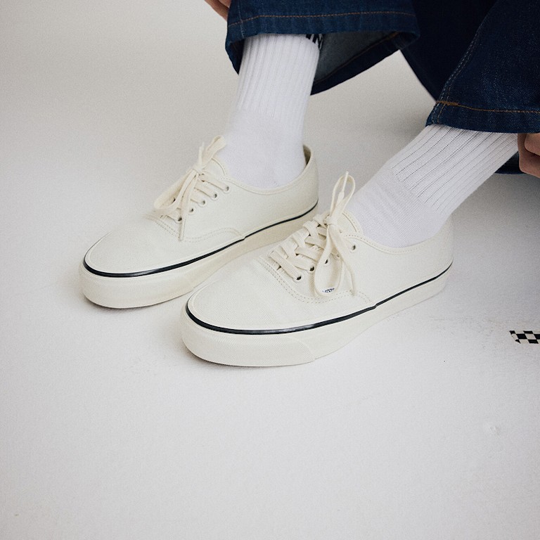 Close up of someone wearing the Premium Authentic Shoe in Marshmallow White on the floor of a grey photography studio.
