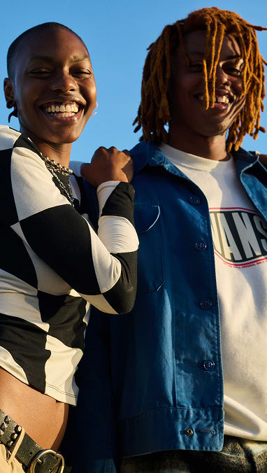 Two people smiling at the camera in a Checkerboard sweater and a Vans logo crewneck.