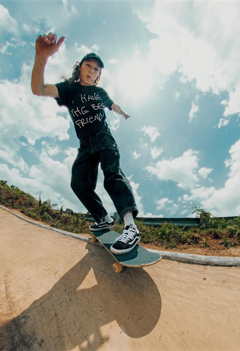 A skater grinding the lip of a bowl wearing black and white Skate Old Skool 36+ with black jeans and a black t-shirt.