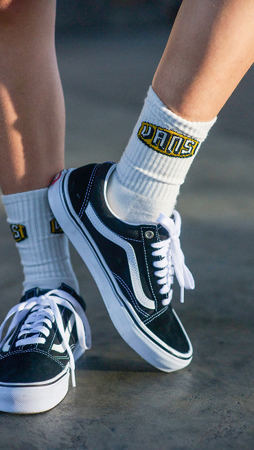 On body close up shot of the black Old Skool shoes, paired with white Vans crew socks.