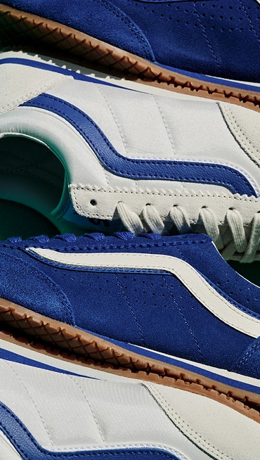 Close up of Super Lowpro shoes in alternating colors of true blue with white Side Stripes and marshmallow white with true blue Side Stripes.