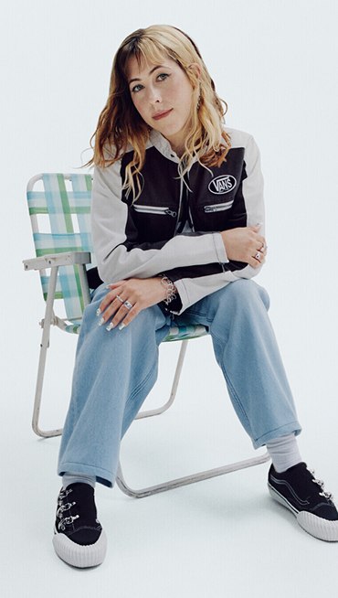Vans Surfer Karina Rozunuko sits and poses on a lawn chair in a photography studio wearing her Premium Old Skool from the New Future collection.