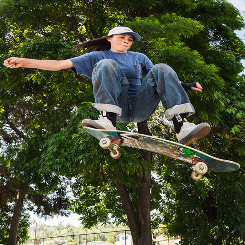 Vans skateboarder Curren Caples does a trick in the air wearing a white t-shirt, black jeans, and white Curren shoes.