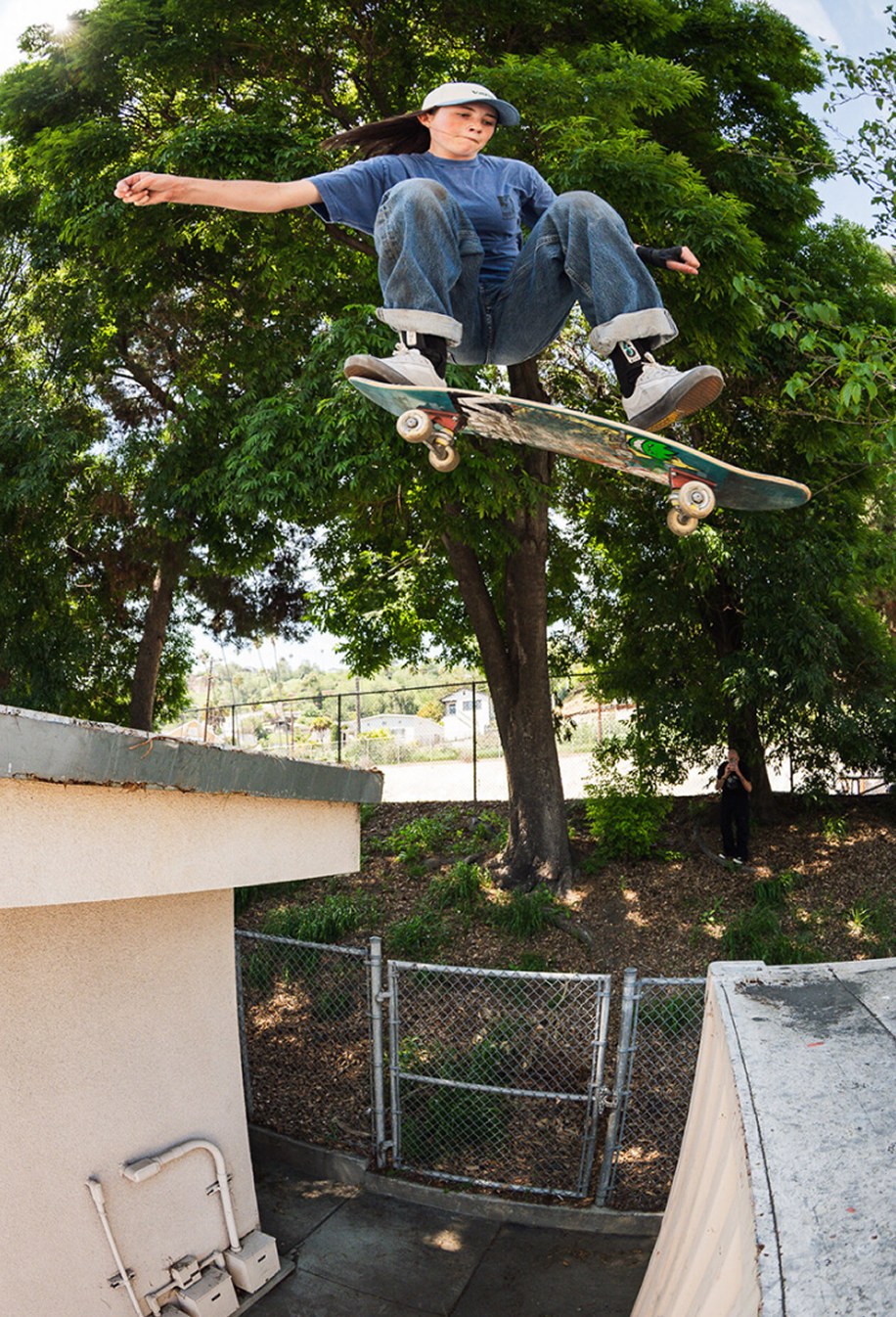 Vans skateboarder Curren Caples does a trick in the air wearing a white t-shirt, black jeans, and white Curren shoes.