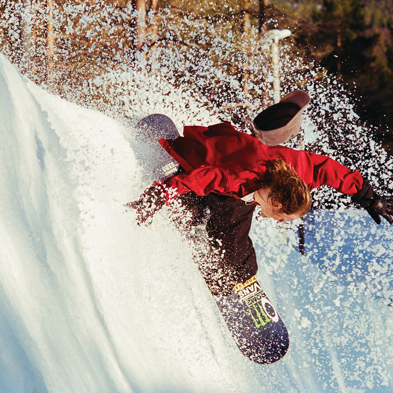 A waist-down shot of someone holding the red and white Encore Pro snowboard boots.