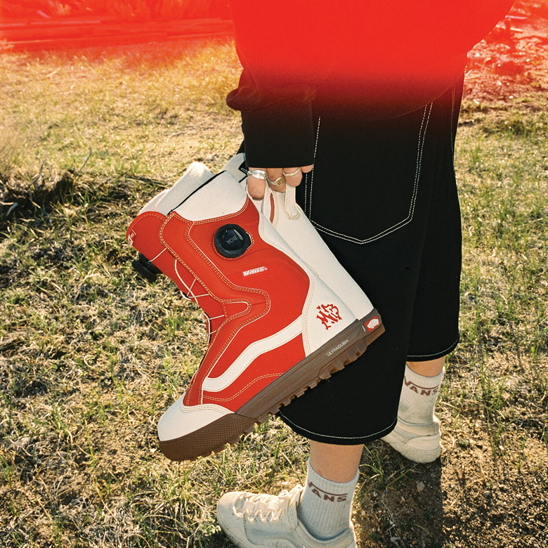 A waist-down shot of someone holding the red and white Encore Pro snowboard boots.