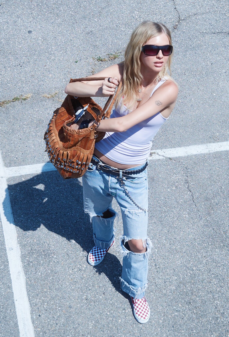 An overhead shot of model Beanie in a parking lot wearing ripped jeans and red Checkerboard Classic Slip-On on the set of Open Set Los Angeles.