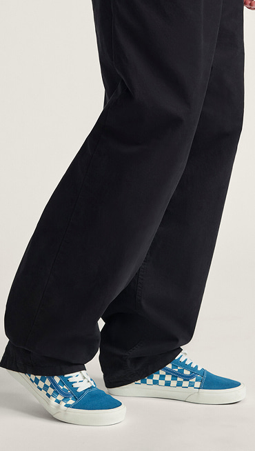 A knee-down shot of a man wearing blue Checkerboard Premium Old Skool paired with black Authentic Chino Relaxed Pants.