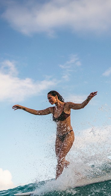 A man with long hair looks at the camera wearing a black and mint Hawaiian shirt and a black Vans bucket hat.