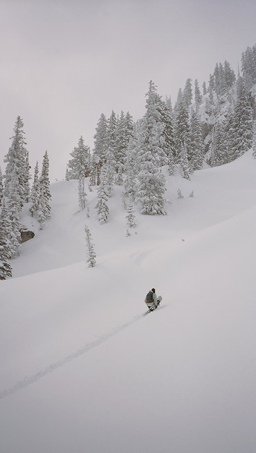 Vans Snowboard Team Rider Cannon Cummins riding a snowboard off a cliff and grabbing his board in the Infuse snowboard boot.