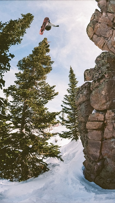 Vans Snowboard Team Rider Cannon Cummins riding a snowboard off a cliff and grabbing his board in the Infuse snowboard boot.