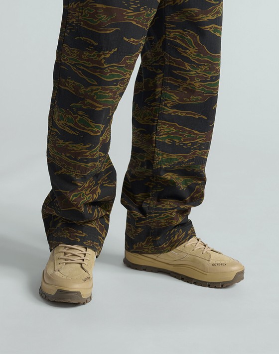 A waist-down shot of a man wearing MTE Sk8-Hi GORE-TEX Insulated boots and Skate Loose Atiba Haze Cargo pants in a photography studio.