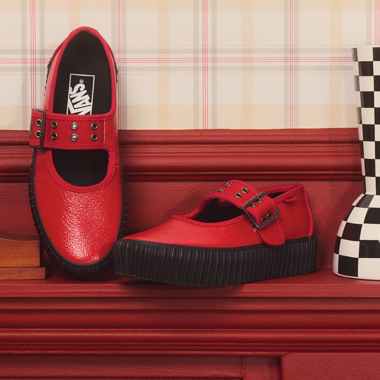 A pair of racing red Mary Jane Creeper rest on the mantle on a TV sitcom set.