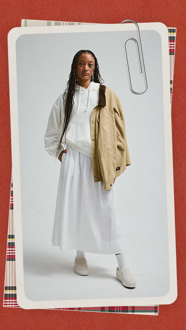 Une bordure rouge des Fêtes entourant l’image d’une jeune femme portant un manteau Drill Chore couleur beige et un chandail rétro Pearls Logo blanc.