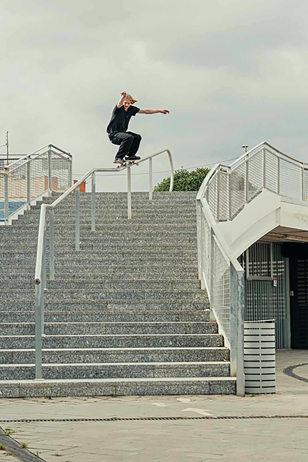 Image of a man skateboarding down a staircase rail.