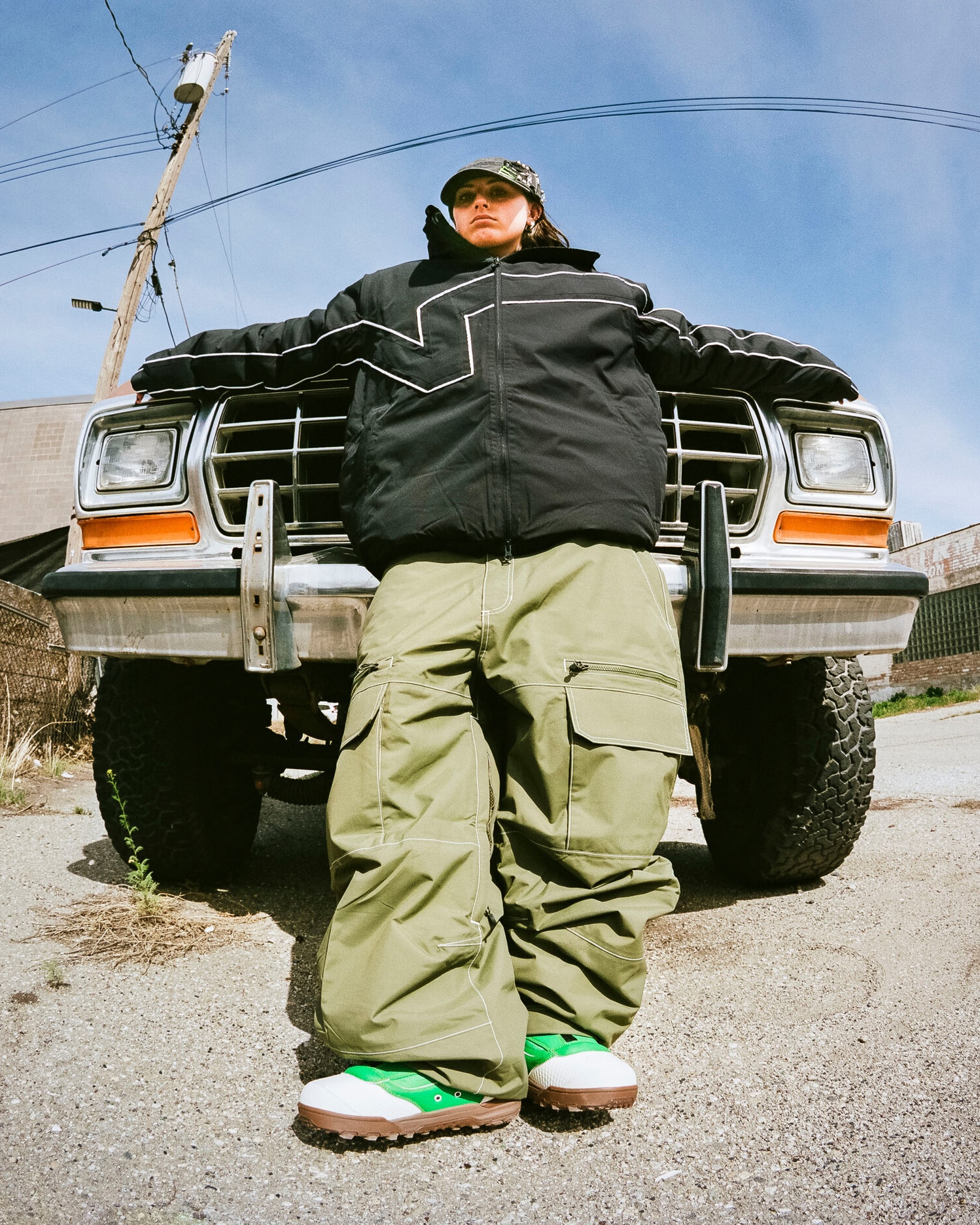 Image of Vans Snow Athlete, Mia Brookes, leaning against the front of a truck wearing Vans snowboarding boots and clothing.