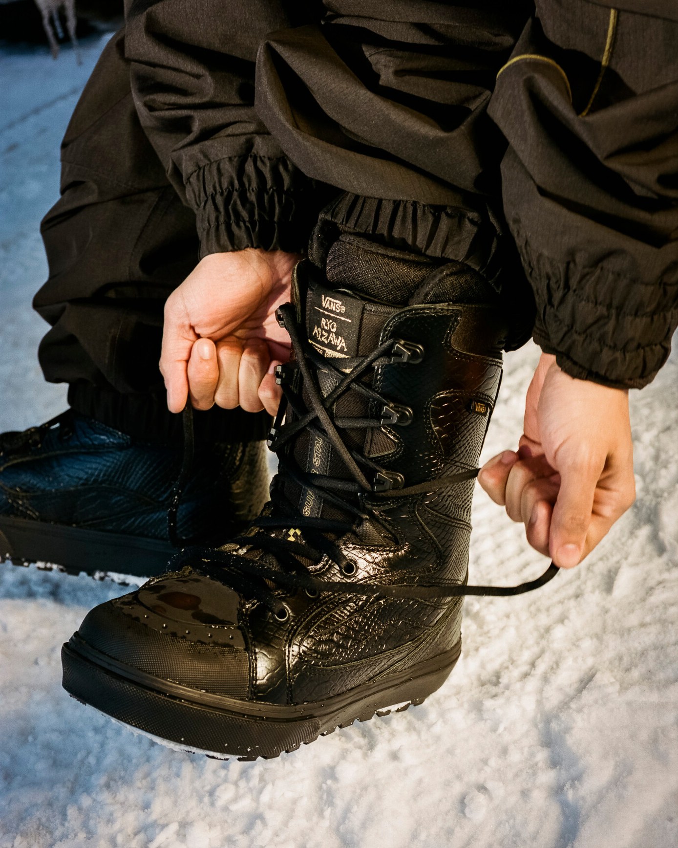Close up image of someone putting on and tying the laces of Vans snowboard boots. 