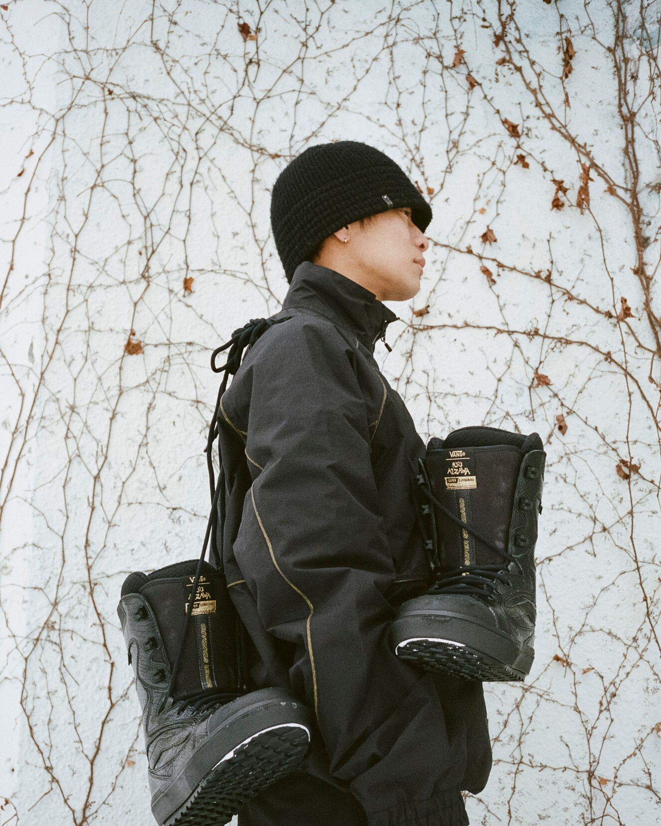 Profile image of Vans Snow Athlete, Ryo Aizawa, with Vans snowboard boots tied at the laces, hanging over his shoulder. 