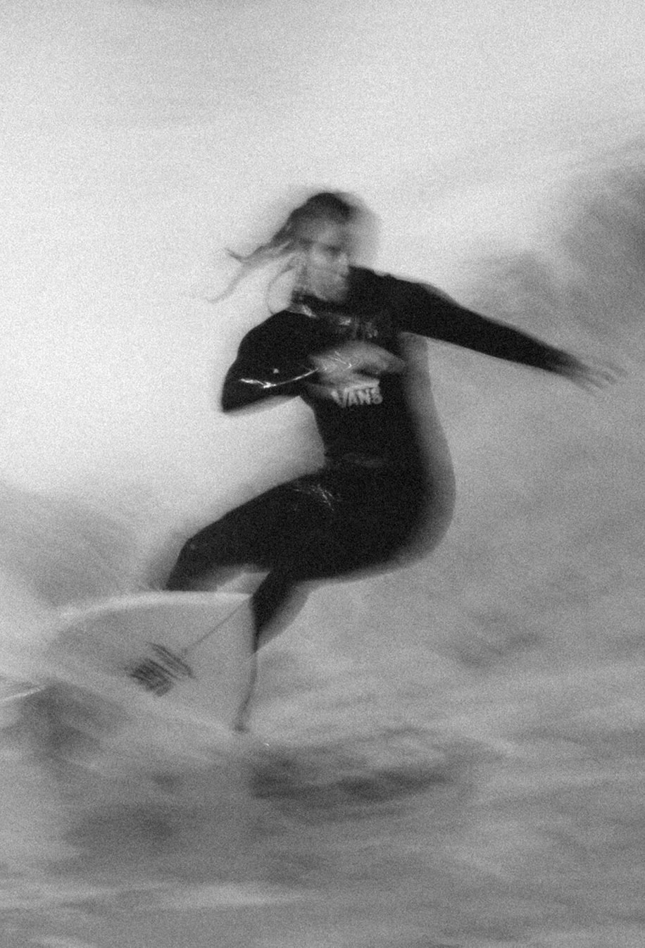A black and white blurry image of a surfer carving on a wave.