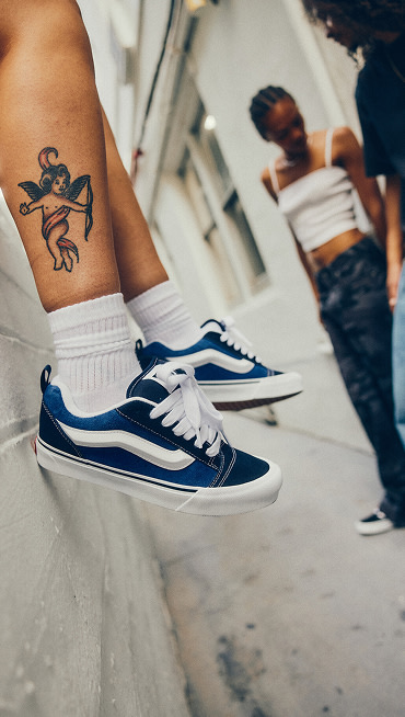 Somebody on concrete stairs wearing the Premium Authentic in Cheetah Pool Blue paired with white quarter socks with the Vans logo.